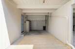 This spacious garage offers ample storage solutions with a tall metal shelving unit and overhead storage racks.