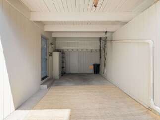 This spacious garage offers ample storage solutions with a tall metal shelving unit and overhead storage racks.