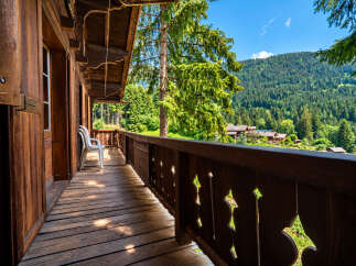Enjoy breathtaking mountain views from the expansive wooden balcony of this charming alpine retreat.
