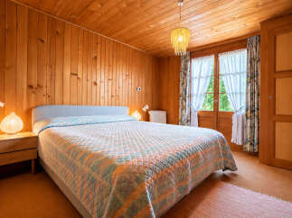 Experience cozy living in this charming bedroom, featuring warm wood-paneled walls and a sloped ceiling that creates an inviting atmosphere.