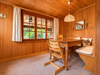 Experience cozy dining in this charming wooden-paneled room, featuring a warm oak table and comfortable bench seating.