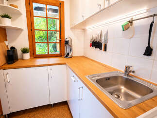 Discover this charming kitchen featuring a sleek stainless steel sink and a durable wooden countertop, perfect for meal preparation.