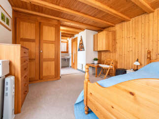 Experience rustic charm in this cozy bedroom featuring warm, natural wood paneling on the walls and ceiling.