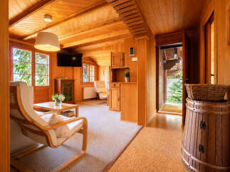 Step into a charming wooden cabin retreat, featuring a cozy living area with a comfortable armchair and a coffee table adorned with fresh flowers.