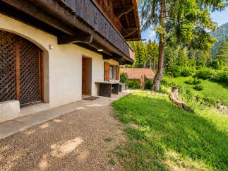 Experience the charm of this rustic alpine property, featuring a traditional wooden balcony overlooking a lush green landscape.