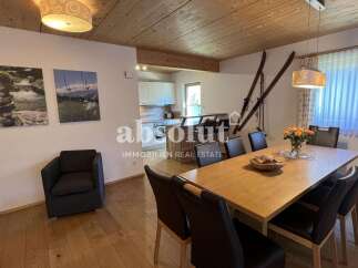 This spacious dining area features a large wooden table surrounded by comfortable chairs, perfect for family gatherings.