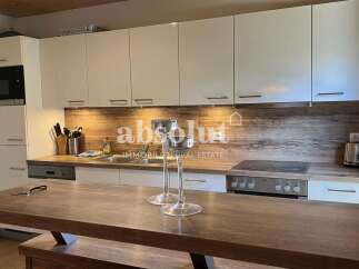 This modern kitchen features sleek white cabinetry and a stylish wood-grain backsplash, creating a warm and inviting atmosphere.