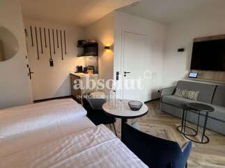 Experience modern living in this stylish studio apartment, featuring a comfortable bed, a compact kitchenette, and a cozy seating area with a sofa and coffee table.