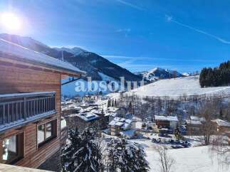 Experience the charm of alpine living in this stunning wooden chalet, offering breathtaking views of snow-capped mountains and a picturesque village.