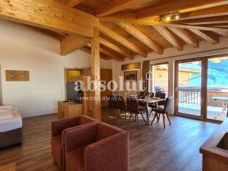 Experience alpine living in this charming apartment featuring exposed wooden beams and a cozy dining area.