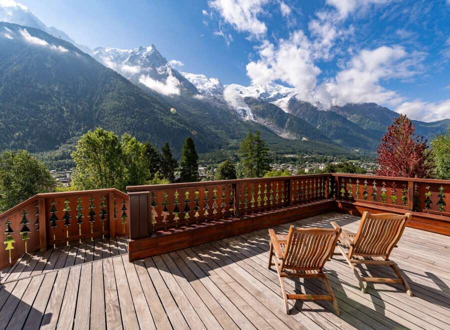 Experience breathtaking mountain views from this stunning wooden deck, complete with two comfortable lounge chairs perfect for relaxation.