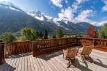 Experience breathtaking mountain views from this stunning wooden deck, complete with two comfortable lounge chairs perfect for relaxation.
