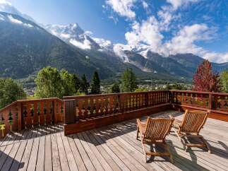 Experience breathtaking mountain views from this stunning wooden deck, complete with two comfortable lounge chairs perfect for relaxation.