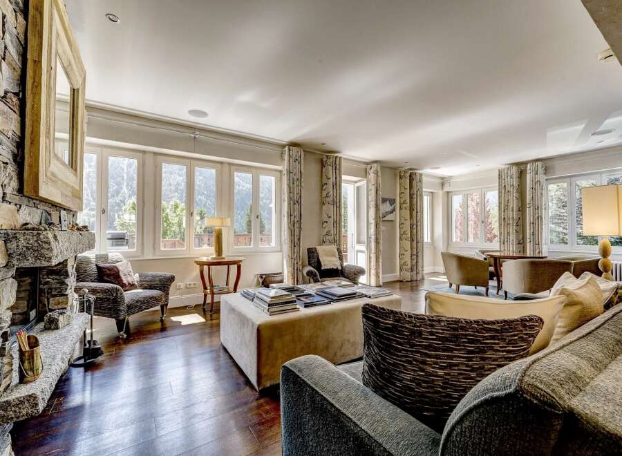 Experience luxurious mountain living in this spacious living room, featuring a grand stone fireplace and large windows that offer breathtaking views of the surrounding landscape.