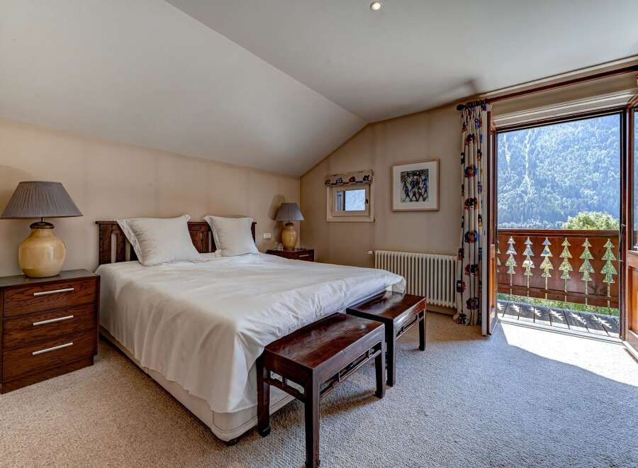 Experience breathtaking mountain views from this charming bedroom, featuring a comfortable king-size bed and elegant wooden nightstands.