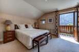 Experience breathtaking mountain views from this charming bedroom, featuring a comfortable king-size bed and elegant wooden nightstands.