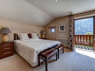 Experience breathtaking mountain views from this charming bedroom, featuring a comfortable king-size bed and elegant wooden nightstands.