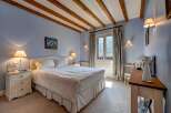 Experience alpine charm in this cozy bedroom featuring exposed wooden beams and a serene blue color palette.