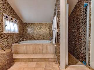 Indulge in luxury with this stunning bathroom featuring a deep soaking tub surrounded by exquisite mosaic tilework.
