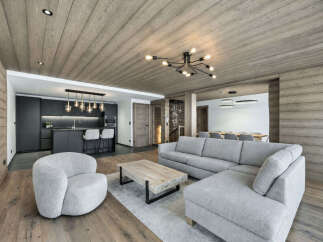 Experience modern mountain living in this stunning open-concept space, featuring a sleek, dark-toned kitchen with a central island and bar stools.