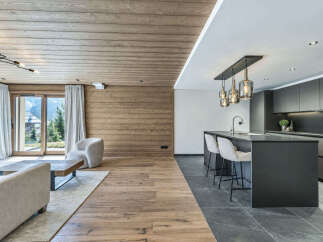 Experience luxury mountain living in this stunning open-concept home featuring a modern kitchen with a sleek island and pendant lighting.