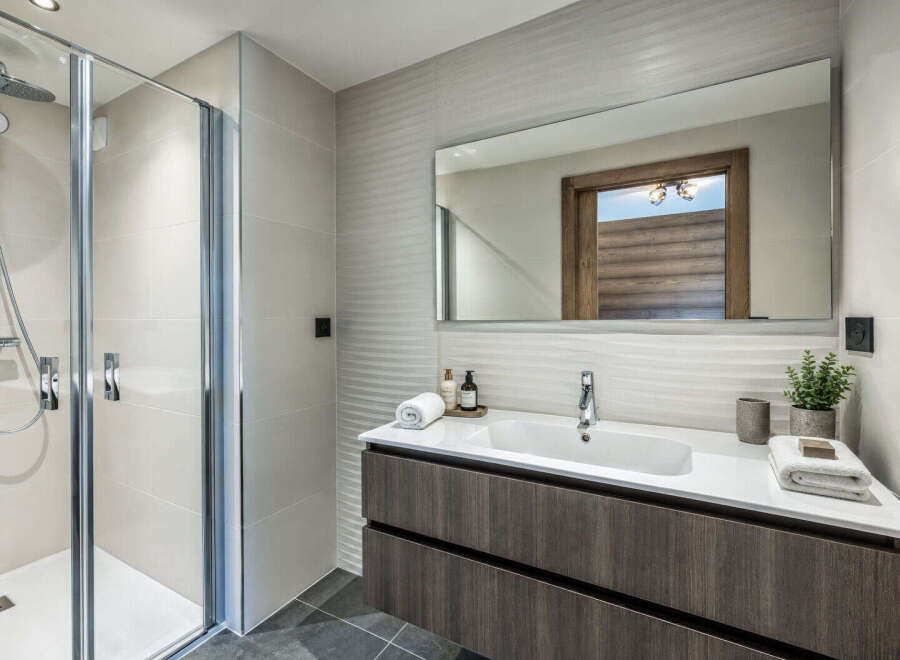 This modern bathroom features a sleek walk-in shower with chrome fixtures and a rainfall showerhead, perfect for a refreshing start to your day.