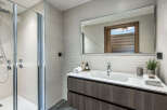 This modern bathroom features a sleek walk-in shower with chrome fixtures and a rainfall showerhead, perfect for a refreshing start to your day.