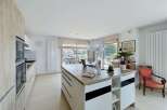 Experience modern living in this spacious kitchen featuring a large island with ample storage and a sleek countertop.