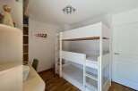 This charming bedroom features a space-saving triple bunk bed, perfect for accommodating multiple guests or children.