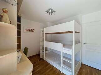 This charming bedroom features a space-saving triple bunk bed, perfect for accommodating multiple guests or children.