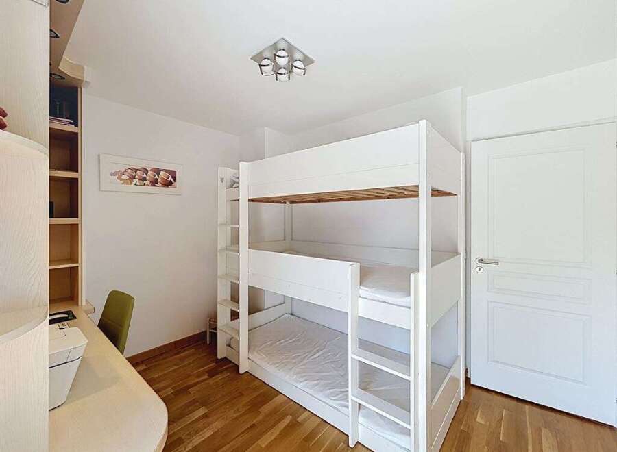 This bright and airy bedroom features a space-saving white bunk bed, perfect for families or guests.