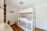 This bright and airy bedroom features a space-saving white bunk bed, perfect for families or guests.