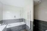 This modern bathroom features a sleek white bathtub with a glass shower screen, perfect for relaxing soaks.