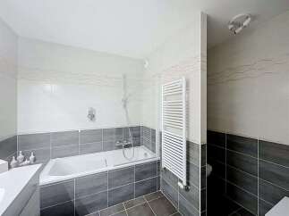 This modern bathroom features a sleek white bathtub with a glass shower screen, perfect for relaxing soaks.