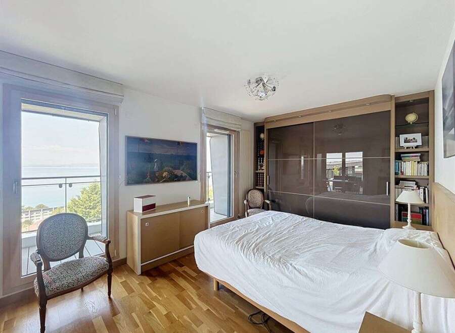 Experience luxurious living in this stunning bedroom featuring a large bed, a wall-mounted TV, and a spacious wardrobe with mirrored doors.