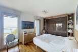 Experience luxurious living in this stunning bedroom featuring a large bed, a wall-mounted TV, and a spacious wardrobe with mirrored doors.