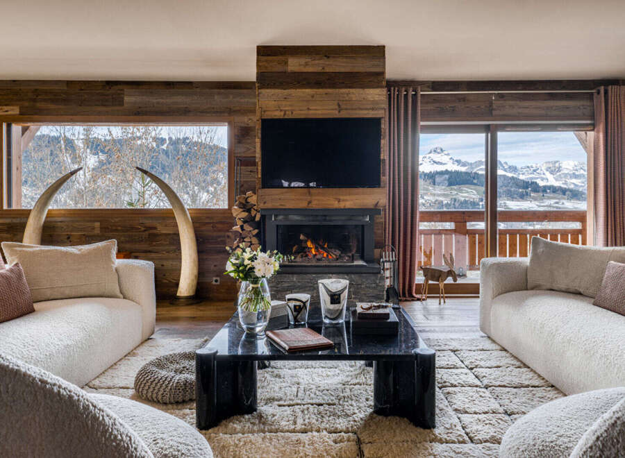 Experience luxurious mountain living in this stunning living room, featuring a cozy fireplace and breathtaking panoramic views of snow-capped peaks.