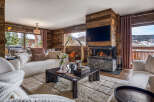Experience luxury mountain living in this stunning chalet living room, featuring a modern fireplace and a large TV mounted on a rustic wood accent wall.