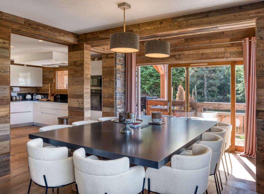 Experience luxurious mountain living in this stunning dining area, featuring a spacious dark wood table surrounded by plush white chairs.