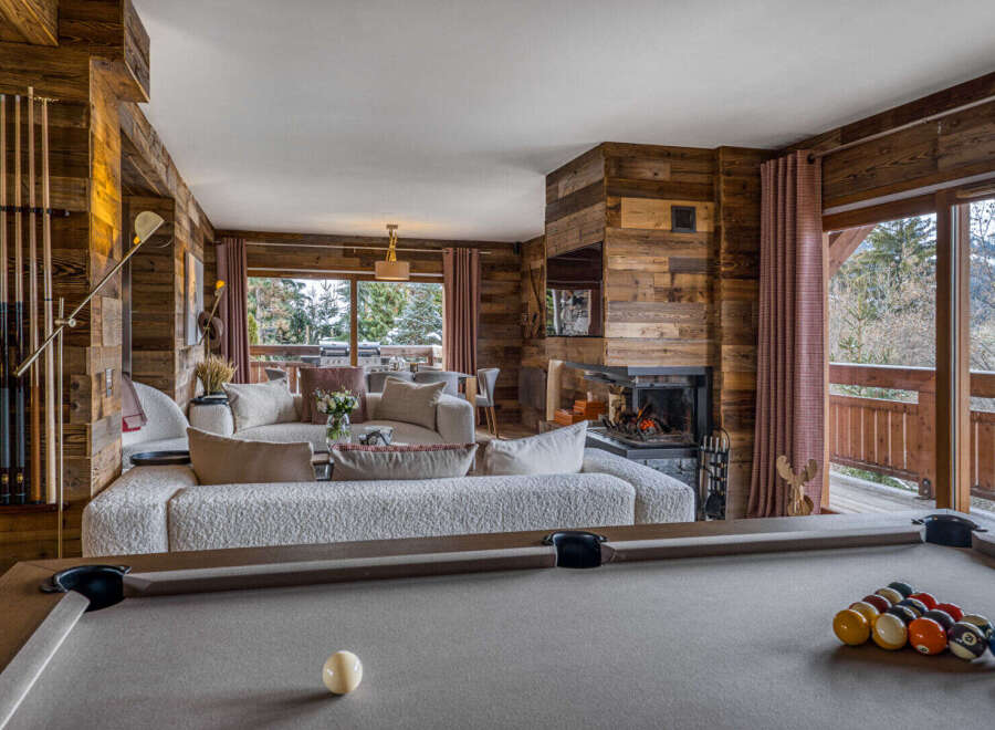 Experience luxury mountain living in this stunning chalet featuring a spacious living area with a cozy fireplace and a billiards table.