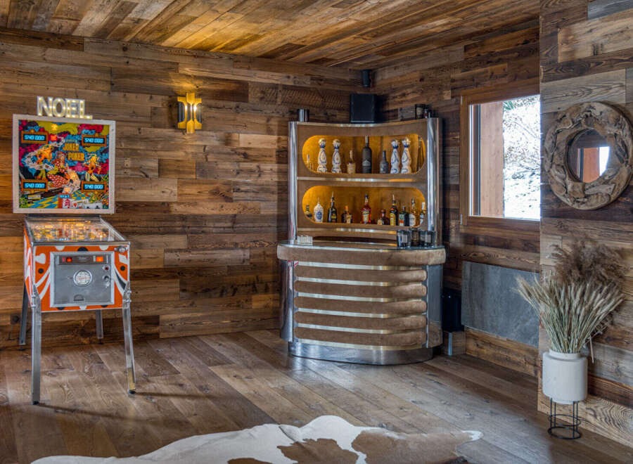 Step into a rustic-chic entertainment haven featuring a vintage pinball machine and a fully stocked bar.