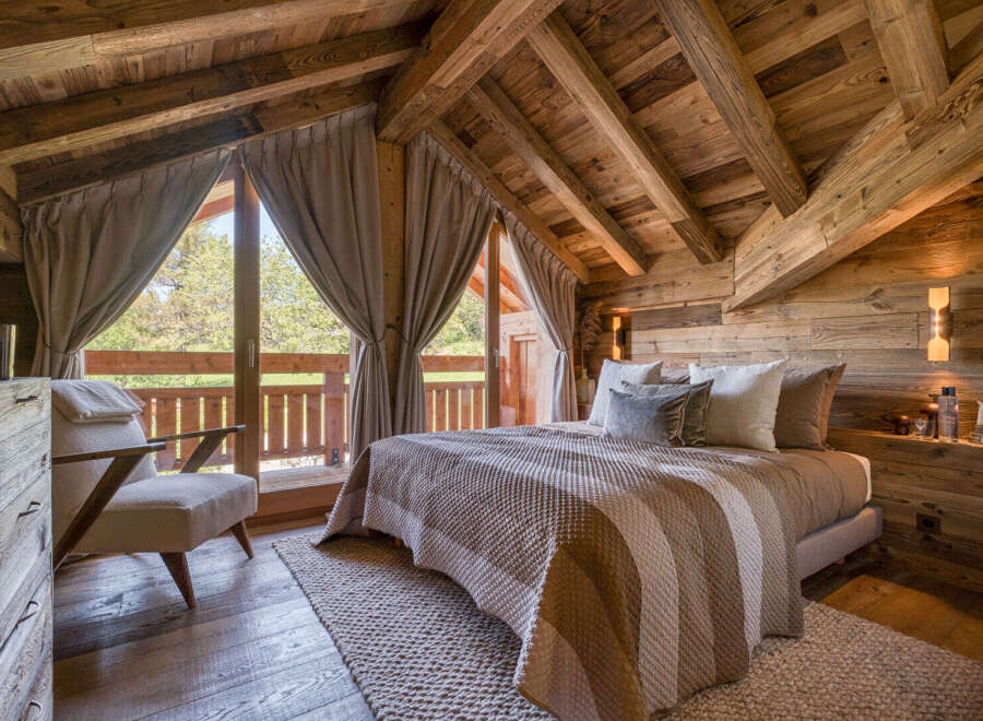 Experience rustic luxury in this charming bedroom featuring a cozy bed with striped bedding and plush pillows.