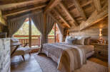 Experience rustic luxury in this charming bedroom featuring a cozy bed with striped bedding and plush pillows.
