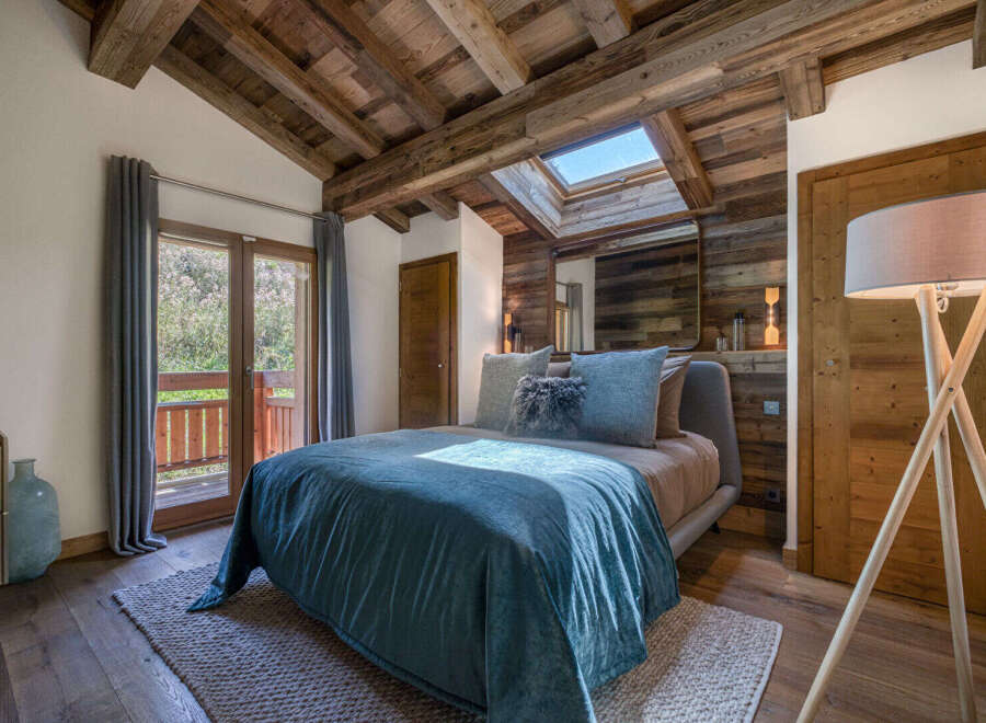 Experience rustic charm and modern comfort in this inviting bedroom, featuring a luxurious bed dressed in serene blue linens.