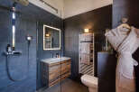 Experience luxury in this modern bathroom, featuring a sleek walk-in shower with a rainfall showerhead and a stylish vanity with a wooden finish.
