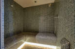 Experience ultimate relaxation in this luxurious steam room, featuring sleek mosaic tilework and comfortable, built-in seating.