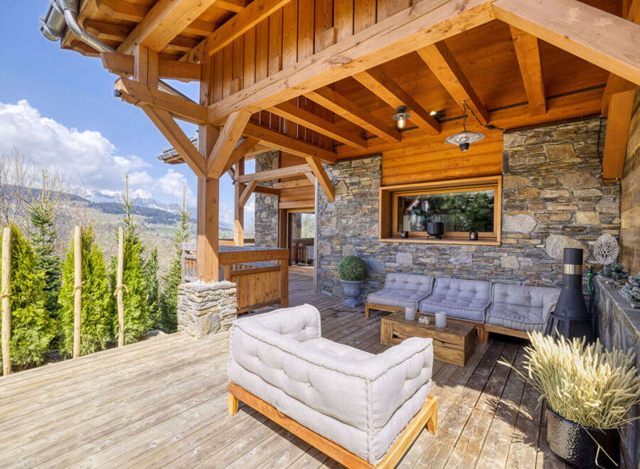 Experience the ultimate mountain retreat with this stunning covered patio, featuring rustic wooden beams and a stone accent wall.