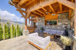 Experience the ultimate mountain retreat with this stunning covered patio, featuring rustic wooden beams and a stone accent wall.