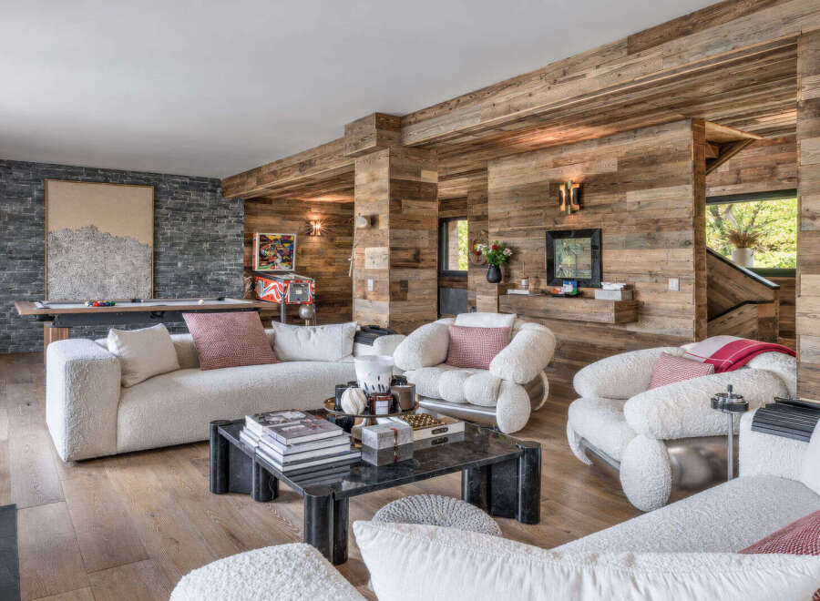 Experience rustic luxury in this mountain retreat living room, featuring a pool table and vintage pinball machine for entertainment.