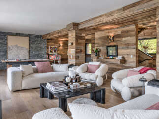 Experience rustic luxury in this mountain retreat living room, featuring a pool table and vintage pinball machine for entertainment.